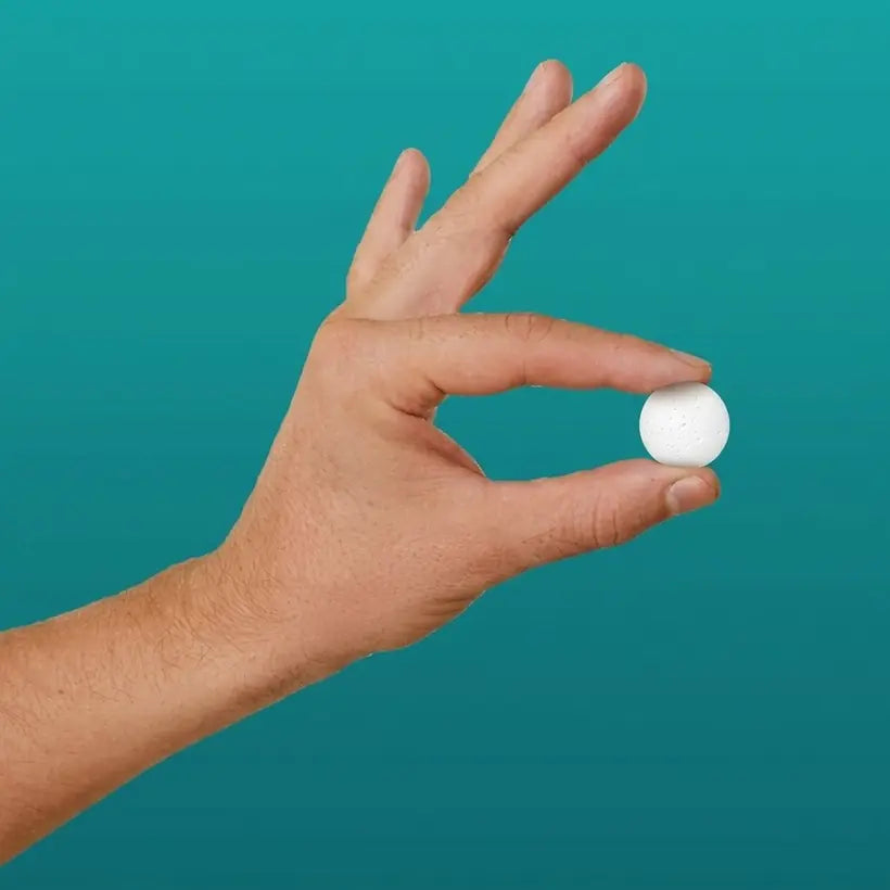 Hand holding a Seaborn soap tablet on a teal background